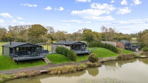 A lakeside property with multiple cabins, each featuring a deck and a covered outdoor seating area.