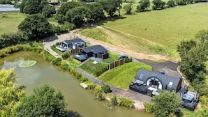 A modern house with a pond, surrounded by lush greenery and a well-maintained lawn.