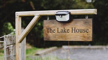 Ein hölzernes Schild mit der Aufschrift 'The Lake House', befestigt an einem Holzpfosten.