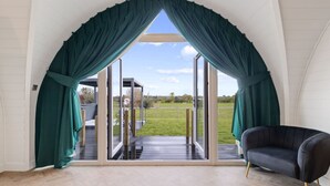 A room with a large sliding glass door leading to a deck, a dark armchair, and a white wall.