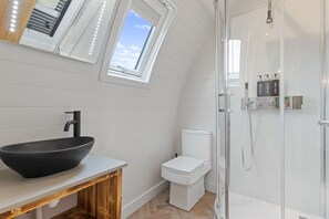 A modern bathroom with a black vessel sink, white toilet, and a glass-enclosed shower. - Nestledstays - The Barn House (Arundel)