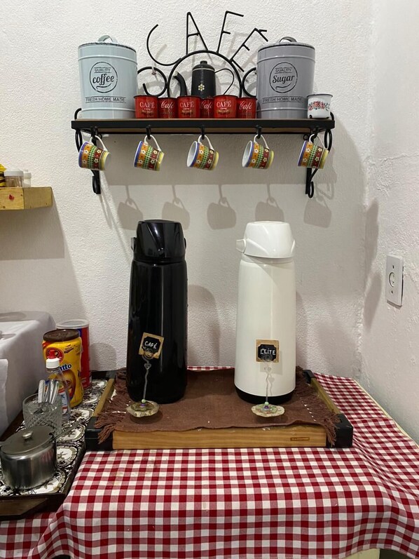 A kitchen area with a coffee station, including a coffee maker, sugar and coffee containers, and a kettle. - Pousada Linda Borboleta (Valenca)