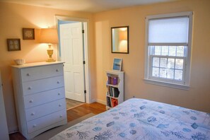 A bedroom with a bed, dresser, bookshelf, and a window with blinds. - Three bedroom central air in South Yarmouth (South Yarmouth)