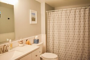 A bathroom with a toilet, sink, and shower curtain. - Three bedroom central air in South Yarmouth (South Yarmouth)