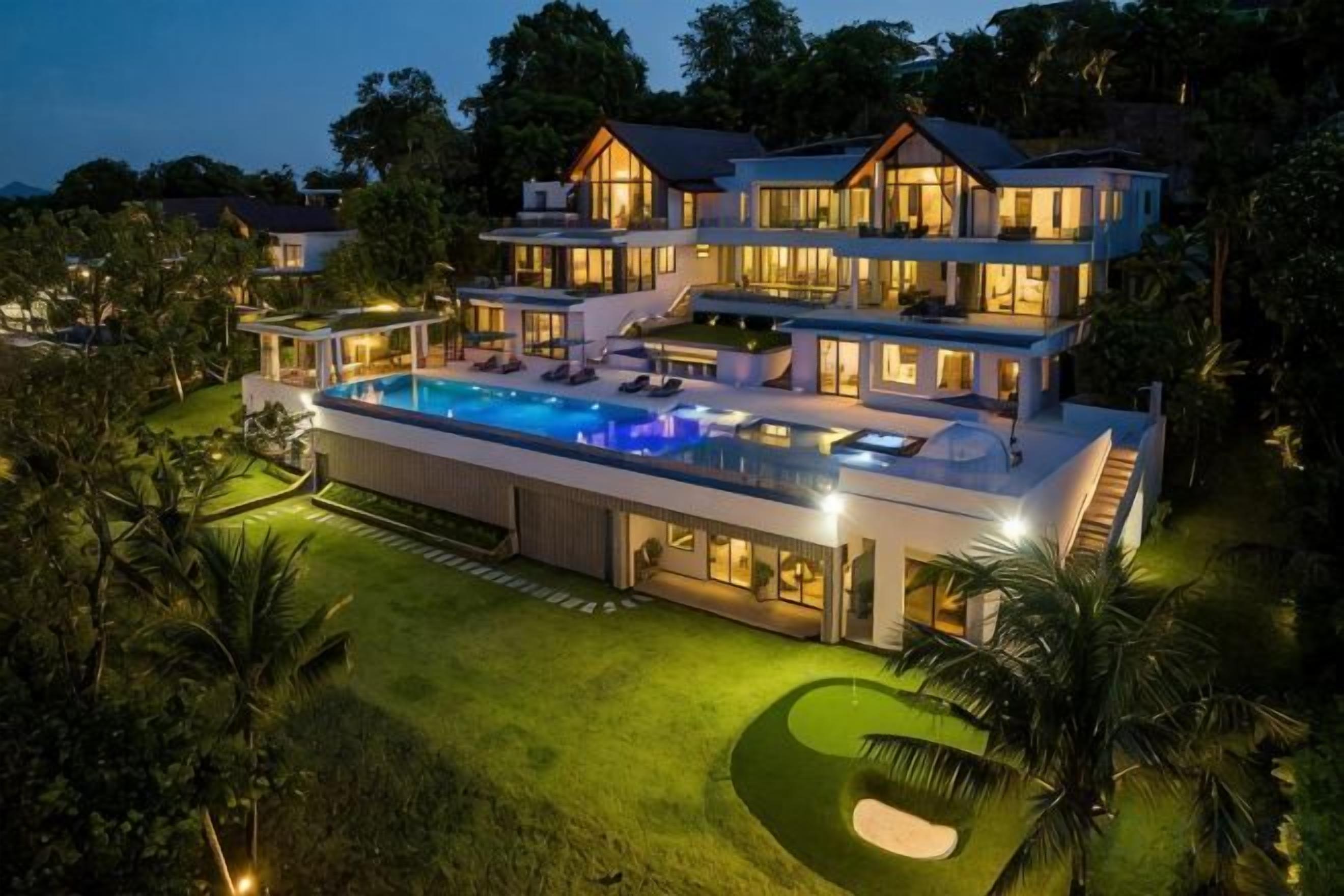 A multi-story house with a swimming pool, surrounded by well-maintained lawns and trees.