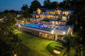 Ein mehrstöckiges Haus mit Swimmingpool, umgeben von gepflegten Rasenflächen und Bäumen.