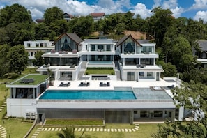 Ein mehrgeschossiges Wohnhaus mit Schwimmbad, mehreren Balkonen und einem gepflegten Rasen.