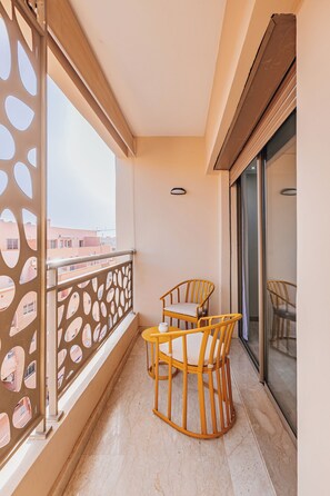 Un balcón con mesa y sillas, un biombo decorativo y vistas a edificios.