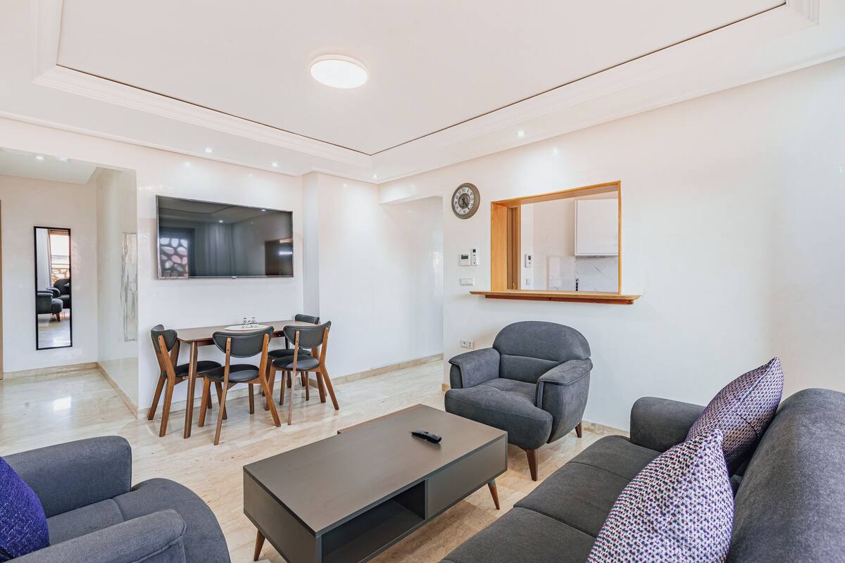 Un salon moderne comprenant un canapé, un fauteuil, une table à manger et des chaises.