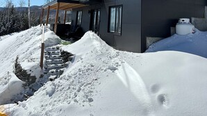 Une maison moderne à deux étages, dotée de grandes fenêtres et d’un porche abrité.