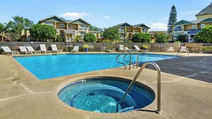 Une piscine avec un jacuzzi, des chaises longues et une vue sur des immeubles d’habitation.
