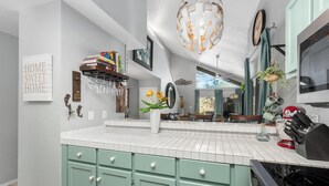 Une cuisine avec des armoires de couleur turquoise, des carreaux blancs et un luminaire suspendu.