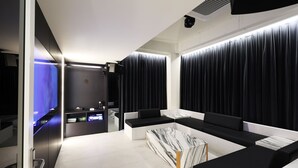 A modern, minimalist room with a sleek black and white color scheme, featuring a large, marble-patterned coffee table, black upholstered seating, and a built-in sound system. - Seoul Inn Hotel by the Designers (Seoul)