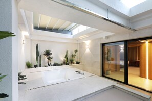A modern bathroom with a large bathtub, skylight, and a glass shower enclosure. - Seoul Inn Hotel by the Designers (Seoul)
