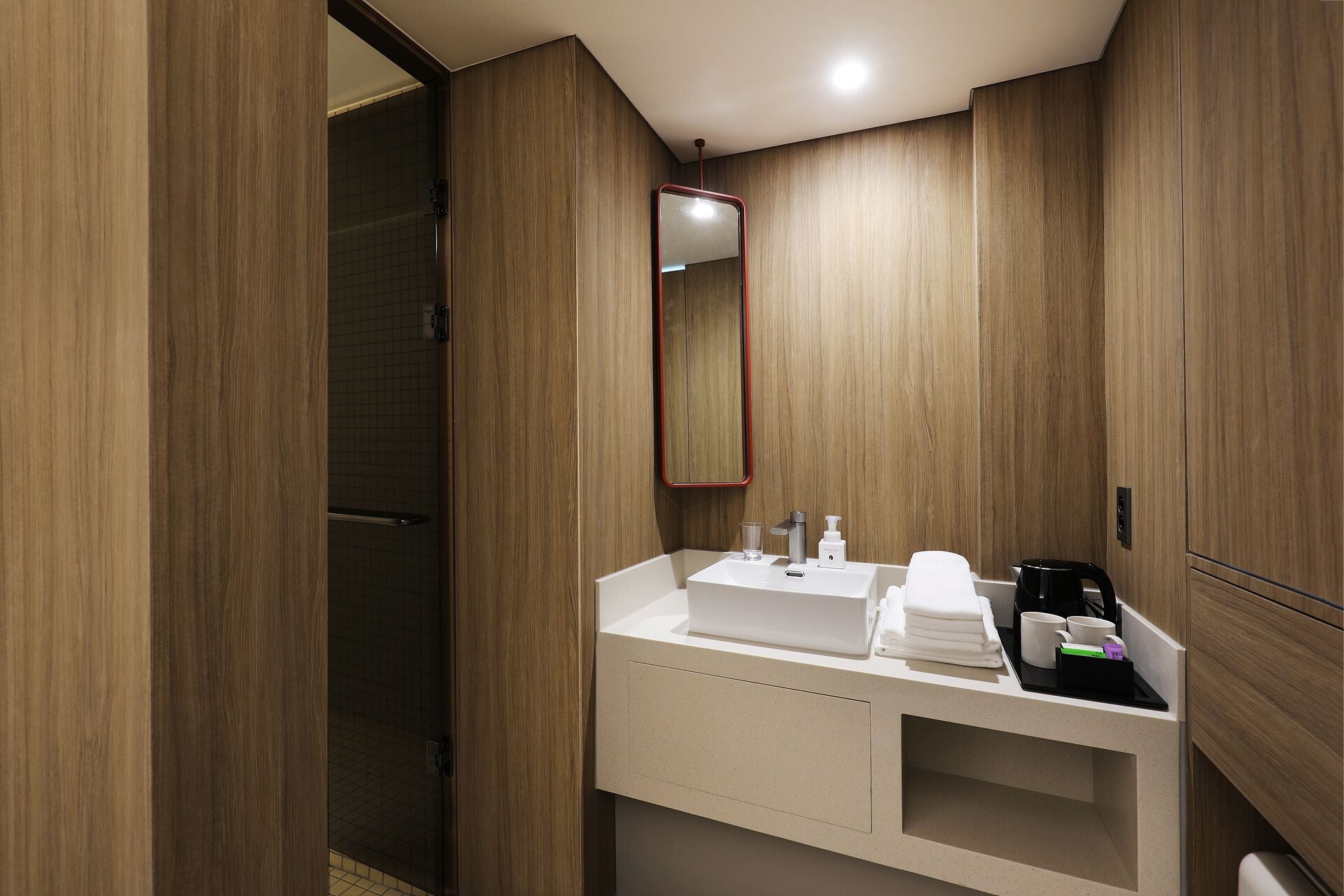 Un bagno moderno con un mobile vanità in legno, uno specchio e una macchina per il caffè.