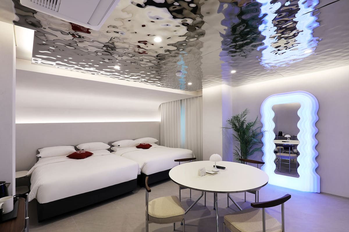 Ein modernes Hotelzimmer mit einem großen Bett, einem runden Tisch und einem außergewöhnlichen Deckendesign.