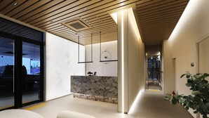 A modern interior with a wooden ceiling, a marble reception desk, and a plant. - Seoul Inn Hotel by the Designers (Seoul)