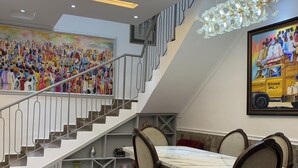 A dining area with a marble table and chairs, a staircase with a railing, and a chandelier. - Signature apartments  (Lekki)