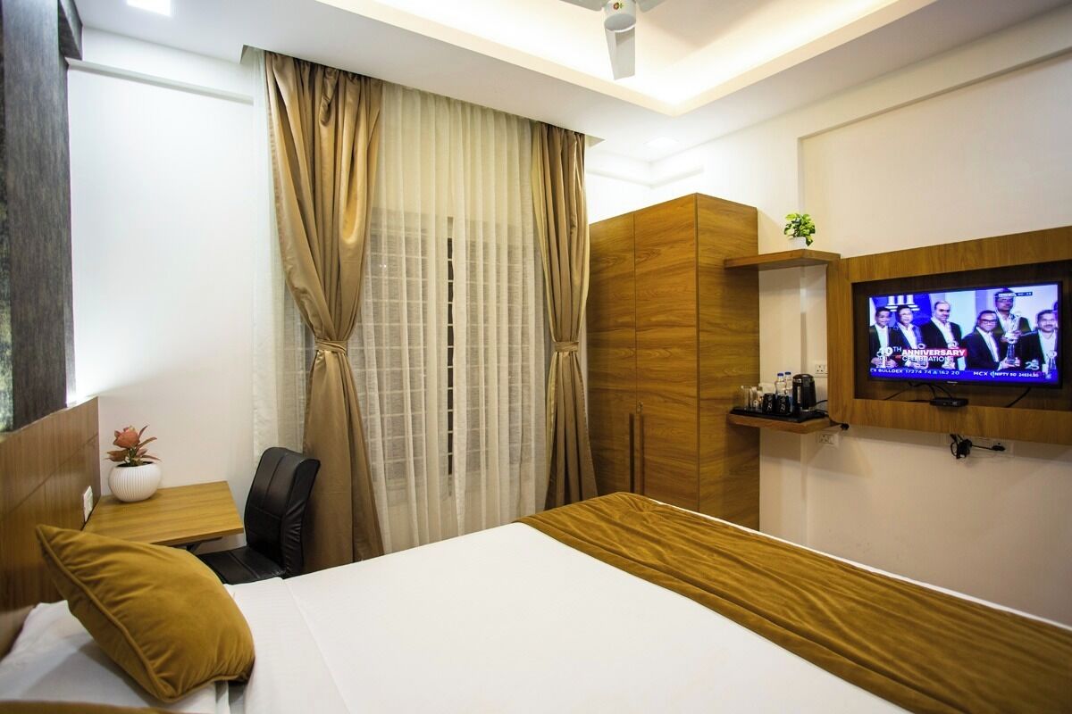 A hotel room with a bed, a desk with a chair, a television, and a wardrobe.
