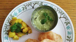 A plate with two fried items, a bowl of green dip, and a side of yellow vegetable dish. - Vintage Villa (Haliyal)