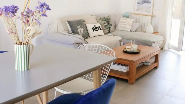 A modern living room with a sofa, a coffee table, a dining table with chairs, and a lamp. - The vacation home, close to town, sea and mountains (Montpellier)