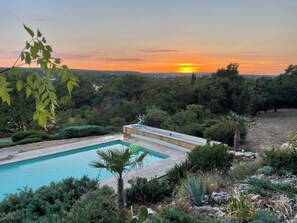 A swimming pool surrounded by lush greenery and a sunset in the background. - Stunning villa in Montmeyan in the Gorges du Verdon in the Var department (Montmeyan)
