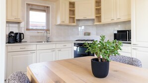 Une cuisine moderne avec des meubles blancs, une table en bois et une plante en pot.