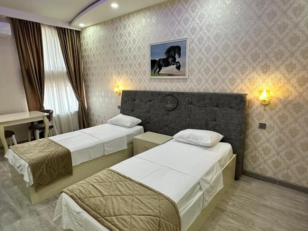 A hotel room with two single beds, a desk, and a chair.