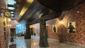 Un vestíbul amb una paret de maó, un rellotge gran i una estàtua.