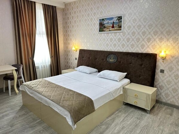Une chambre d’hôtel avec un grand lit, un bureau et deux lampes fixées au mur.
