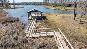 A wooden dock extending into a lake with a covered seating area.