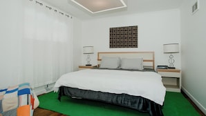 A hotel room with a large bed, two bedside tables, a wall-mounted light fixture, and a patterned wall decoration. - Cozy Mid-Century Mod by Lake MI&Dunes with Hot Tub (Sawyer)