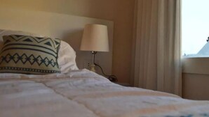 A hotel room with a bed, a pillow with a geometric pattern, a bedside lamp, and a window with curtains. - Maria Pyramids House - Superior King Room (Giza Governorate)