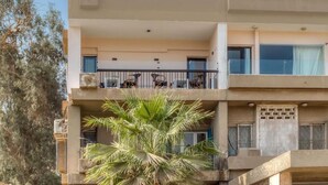 A multi-story building with balconies, a palm tree in the foreground, and a clear sky. - Maria Pyramids House - Superior King Room (Giza Governorate)