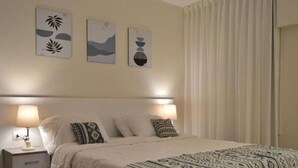 A neatly made bed with a white headboard, two bedside lamps, and a patterned bedspread. There are three wall-mounted artworks above the bed. - Maria Pyramids House - Superior King Room (Giza Governorate)