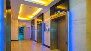 A hotel corridor with elevators, a tiled floor, and a ceiling with recessed lighting. - Master House Centrestage PJ (Petaling Jaya)