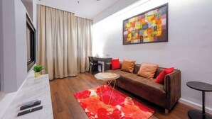 A modern living room with a sofa, a dining table, a ceiling fan, and a colorful abstract painting on the wall. - Master House Centrestage PJ (Petaling Jaya)