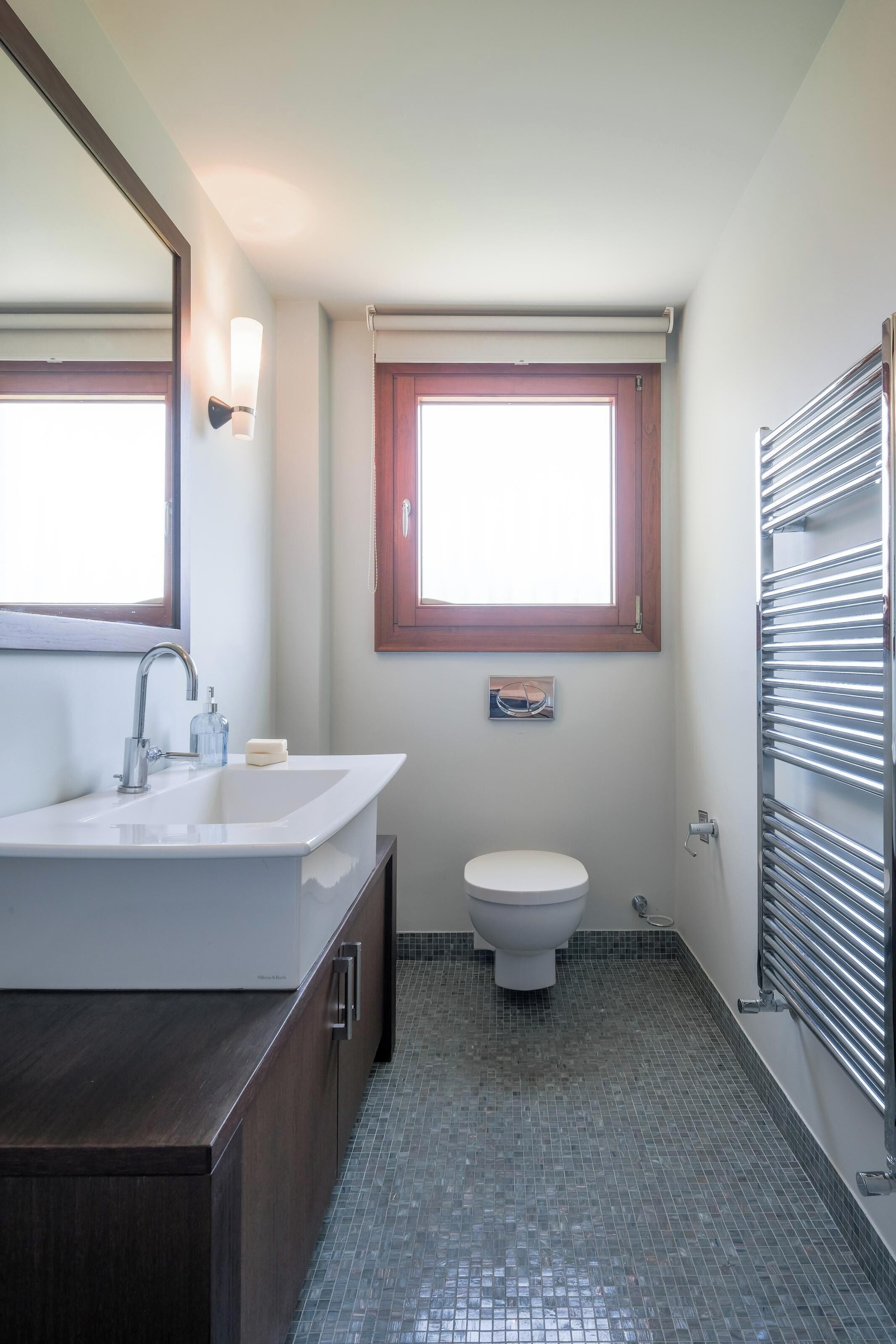 A bathroom with a white sink, a toilet, and a window above the toilet.