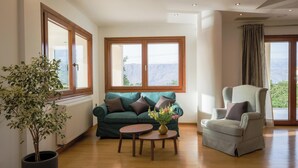 Un salon avec un canapé vert, une table ronde, une plante en pot et un fauteuil gris.
