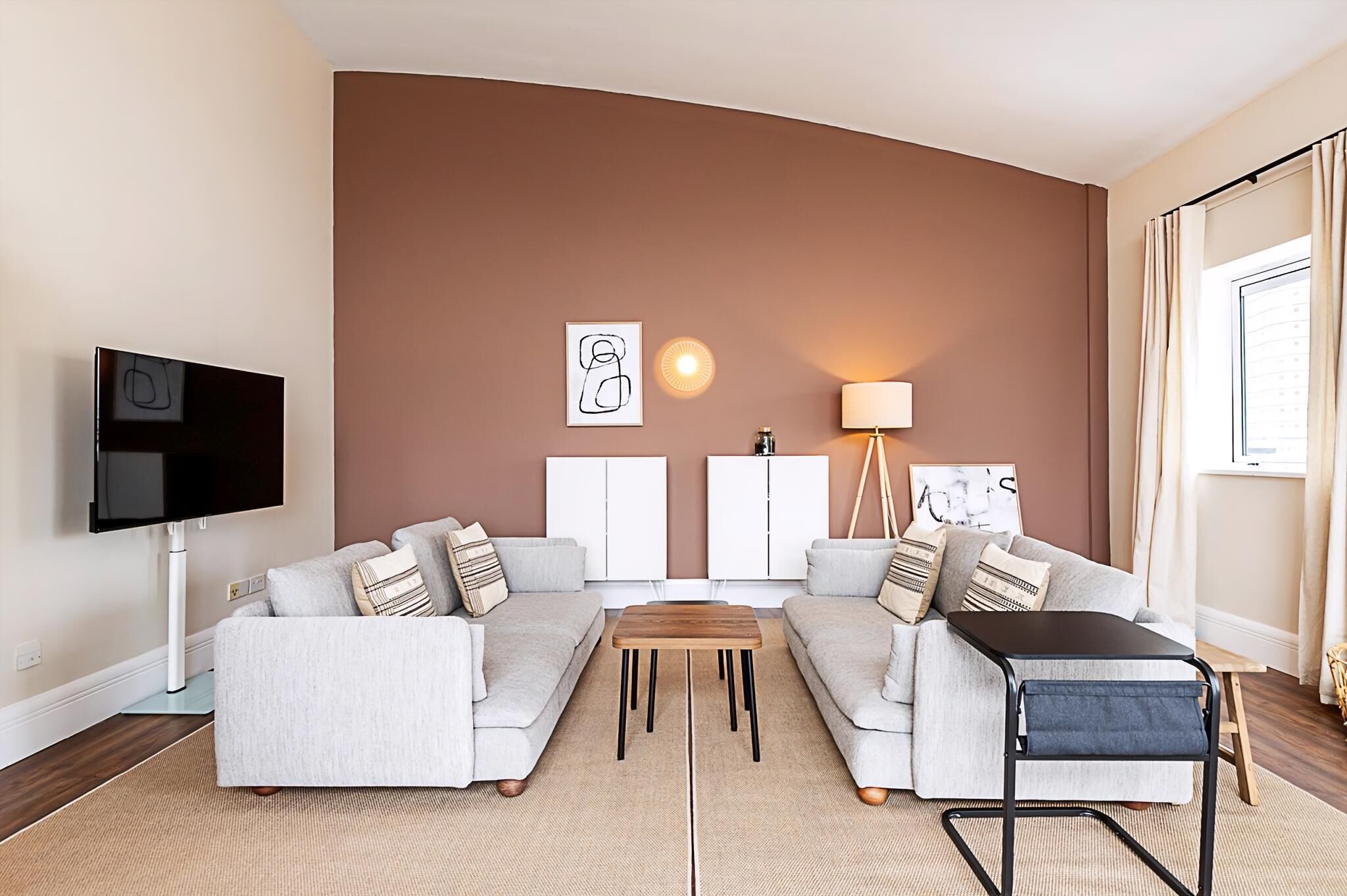 A modern living room with a sofa set, a coffee table, a TV, and a lamp.