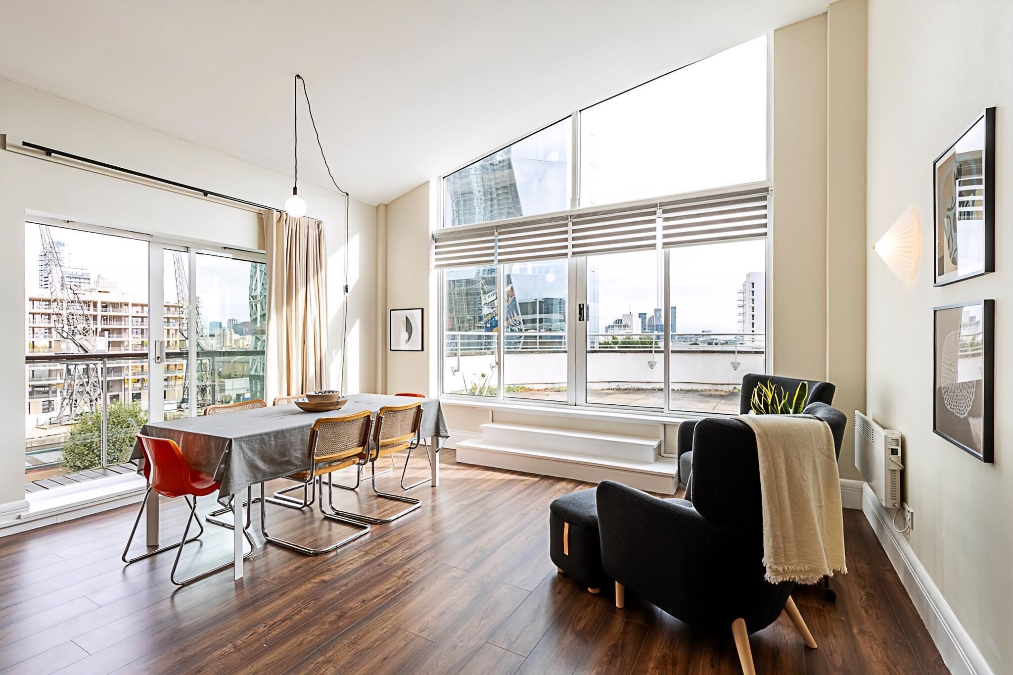 A modern living room with a dining area, large windows, and a city view.