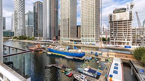 Une vue sur la ville, avec des immeubles de grande hauteur le long du littoral, un quai avec des bateaux, et un ciel dégagé.