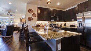 A modern kitchen with dark cabinetry, stainless steel appliances, and a granite countertop. - Incredible Remodeled Luxury Condo (Dillon)