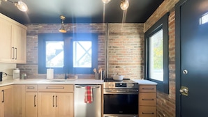 A kitchen with wooden cabinets, a stainless steel dishwasher, a black oven, and a window with a view of the outdoors. - Urban 2-bedroom Escape in Downtown Cape Girardeau  (Cape Girardeau)