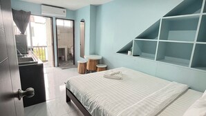 A bedroom with a bed, a desk, a chair, a mirror, and a built-in shelving unit. - Little Seoul (Chiang Mai)