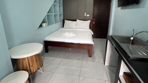 A bedroom with a bed, a small table, a TV, and a sink. - Little Seoul (Chiang Mai)