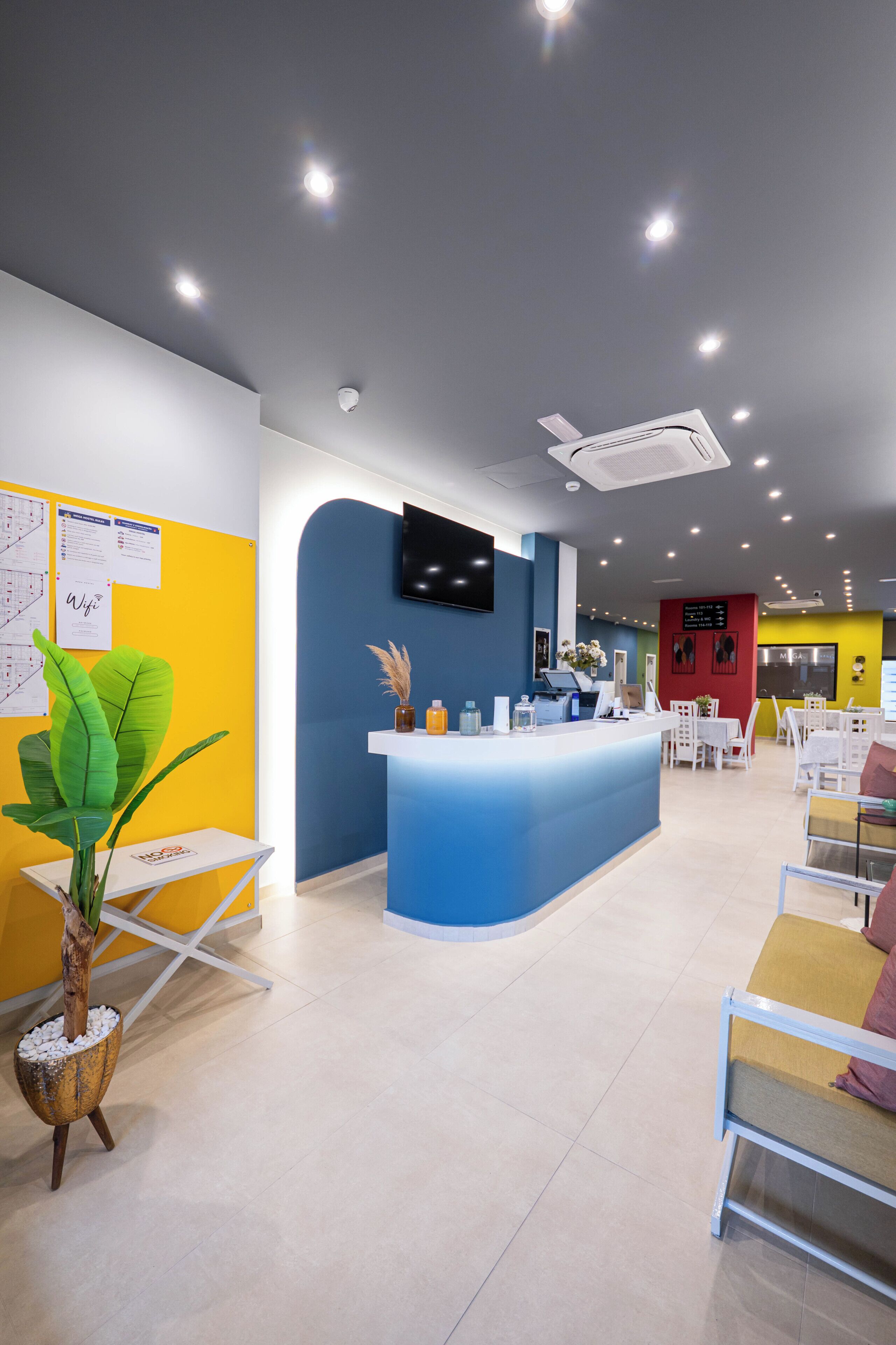 A reception area with a blue counter, white chairs, and a plant.