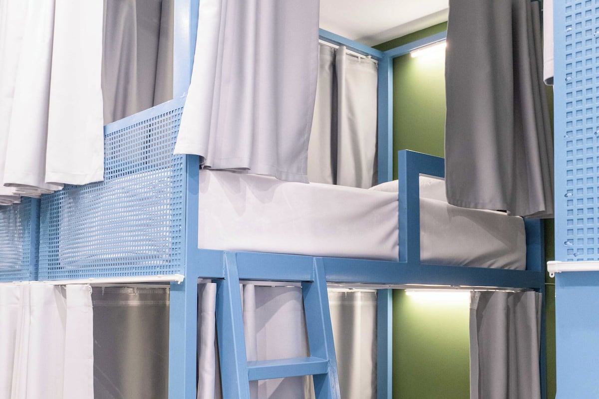 A bunk bed with a ladder, white bedding, and grey curtains.