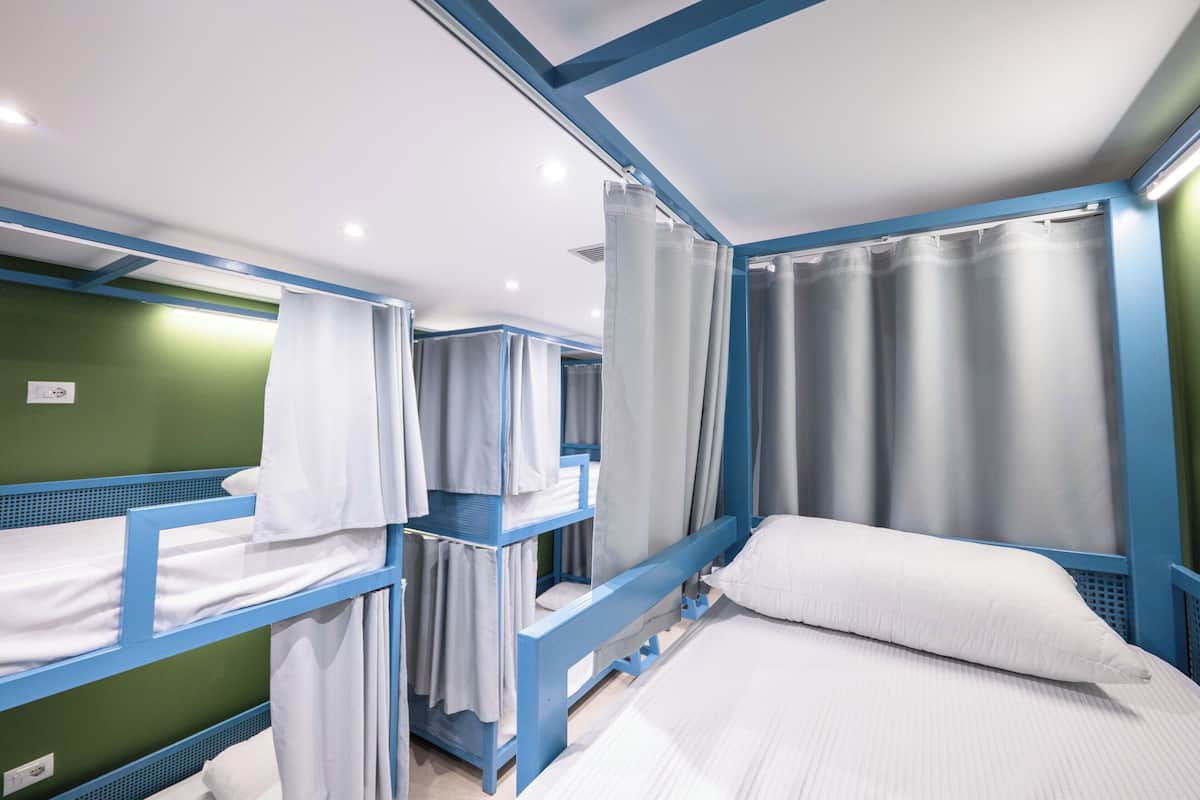 A room with bunk beds, a curtain, and a bed with a pillow.