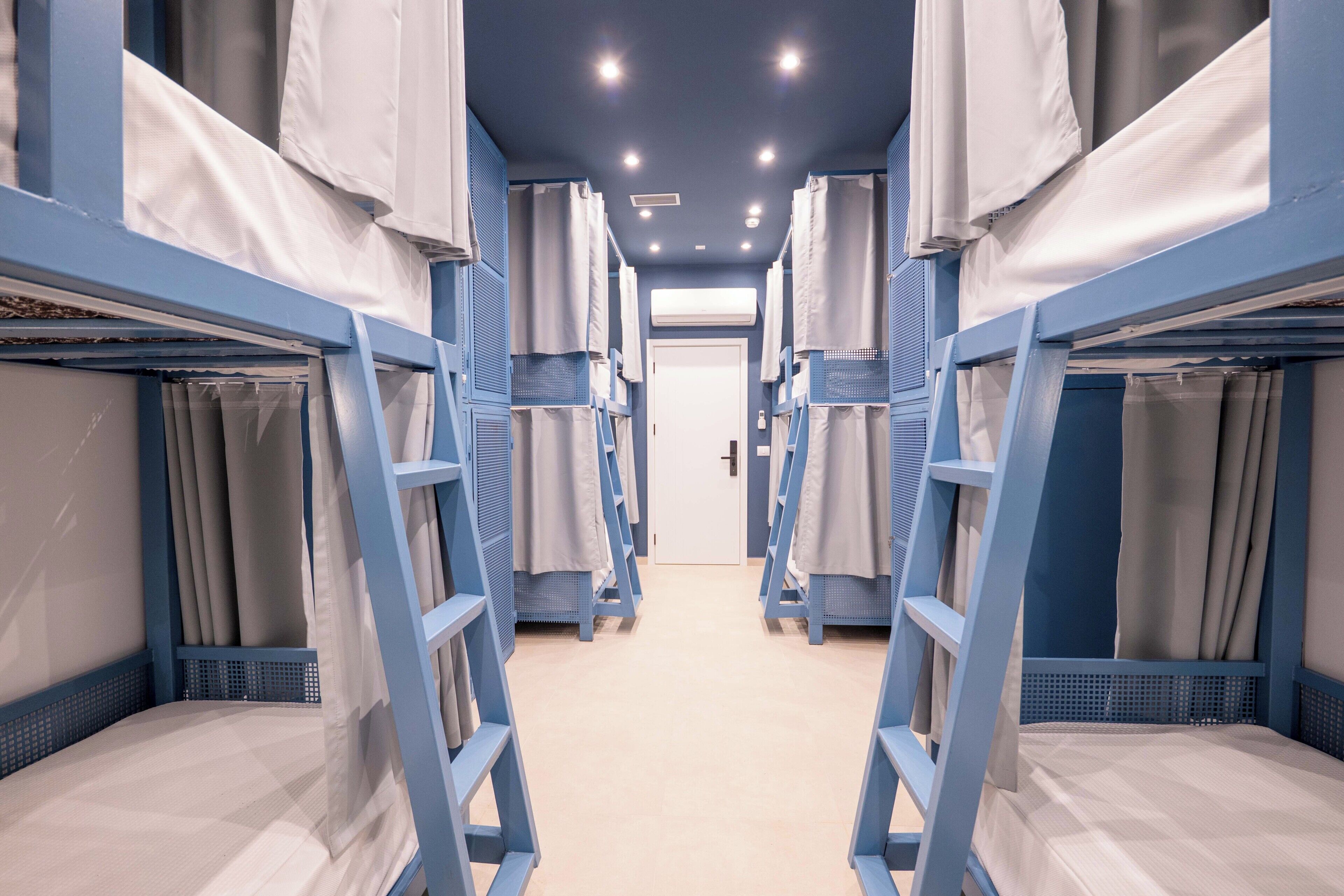 A corridor with bunk beds, each with a ladder and a curtain.